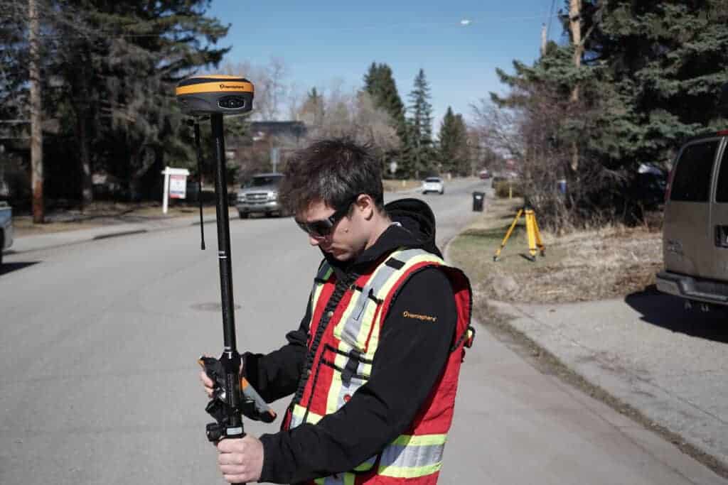 Man using GNSS equipment in the street. Specifically a Hemisphere S631 reciever. 