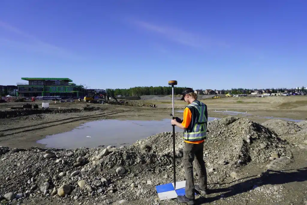 Surveyor with a GNSS rover establishing a property boundary point on an active subdivision development site