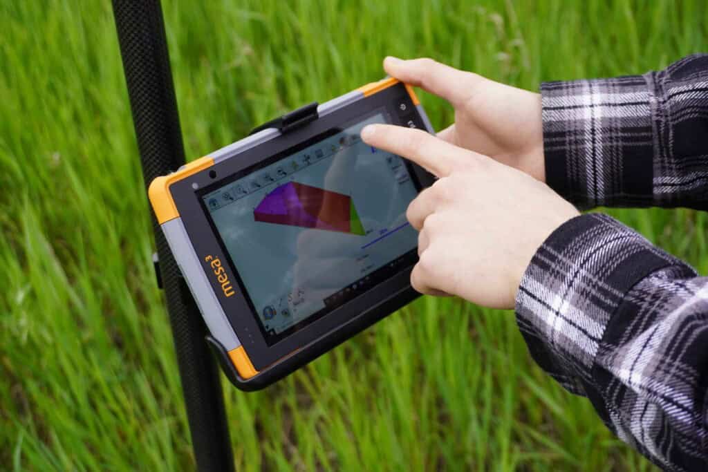 Surveyor using FieldGenius software on a Juniper Mesa 3 tablet for land surveying.