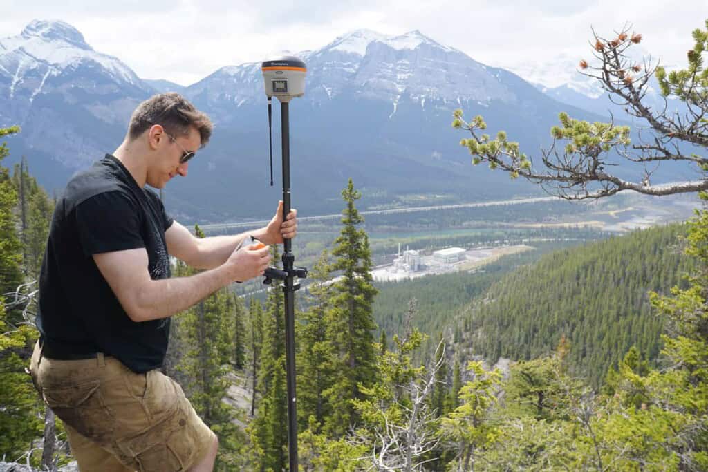 Surveyor adjusting equipment on mountain with valley view
