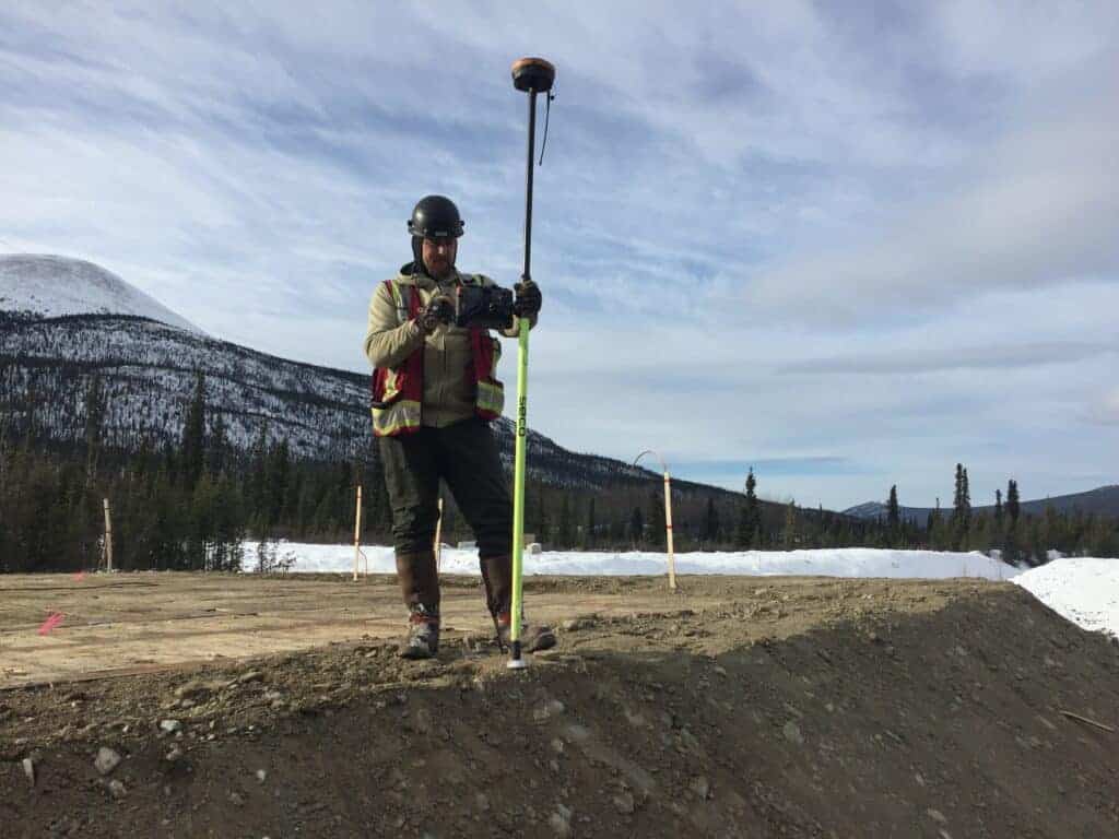 Worker using surveying instrument in mountains