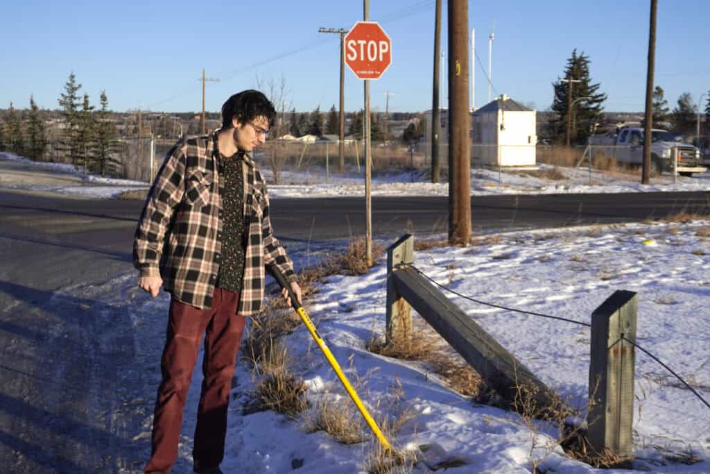 Surveyor using magnetic locator to locate buried survey pin