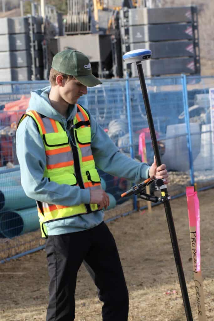Surveyor using RTK GNSS receiver marking control point for road construction layout