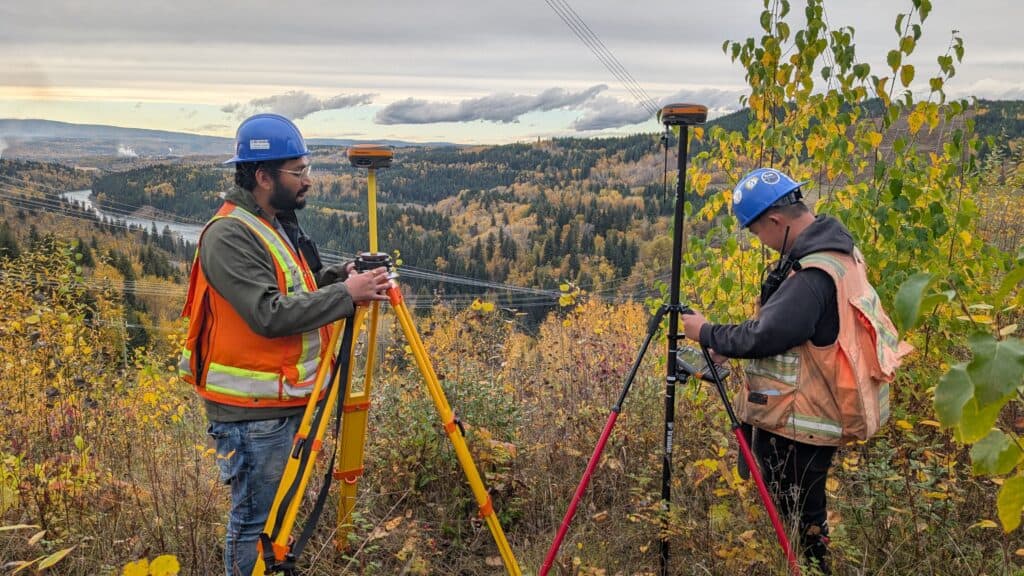 Surveyors setting up GNSS receivers on tripods during field surveying