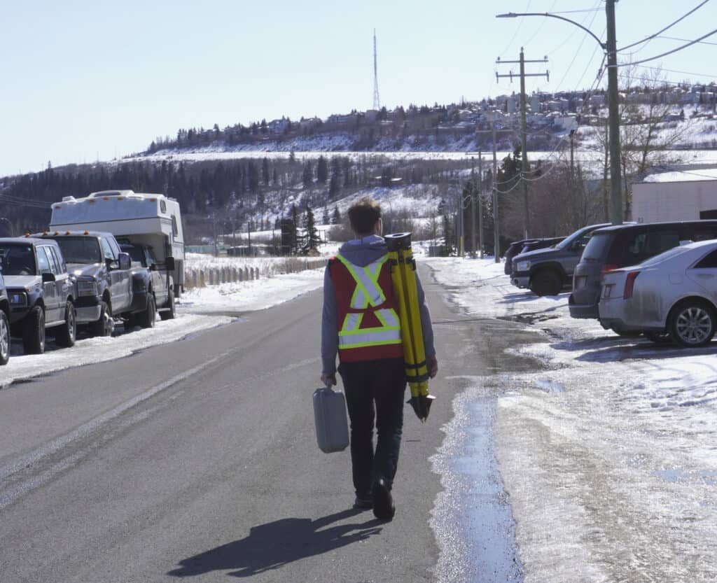 Surveyor carrying a surveying tripod during winter field work