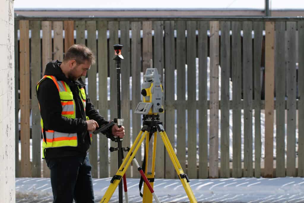 Surveyor operating total station on tripod for construction layout and measurement